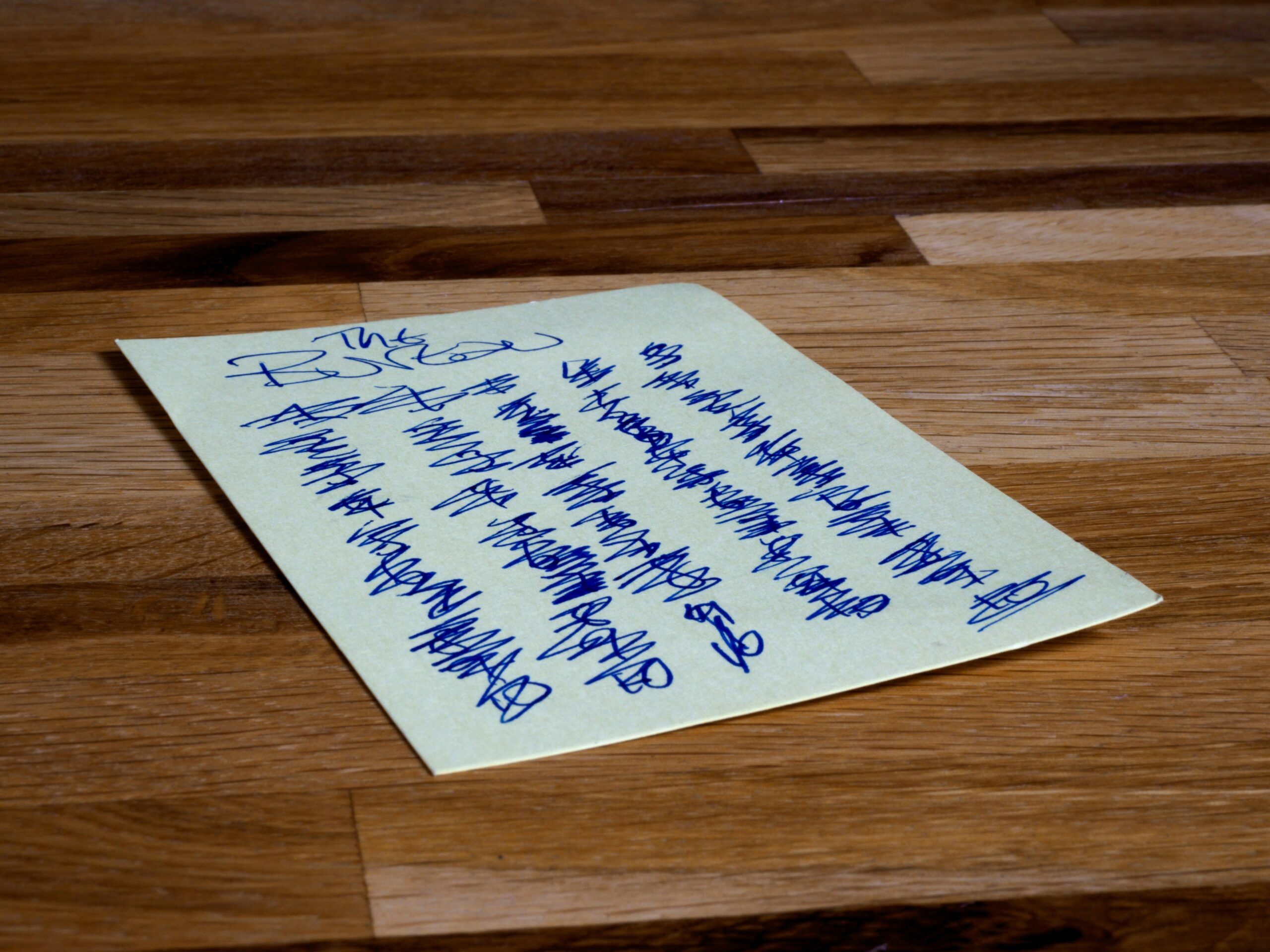 A disorganized handwritten grocery list scattered across a messy counter.