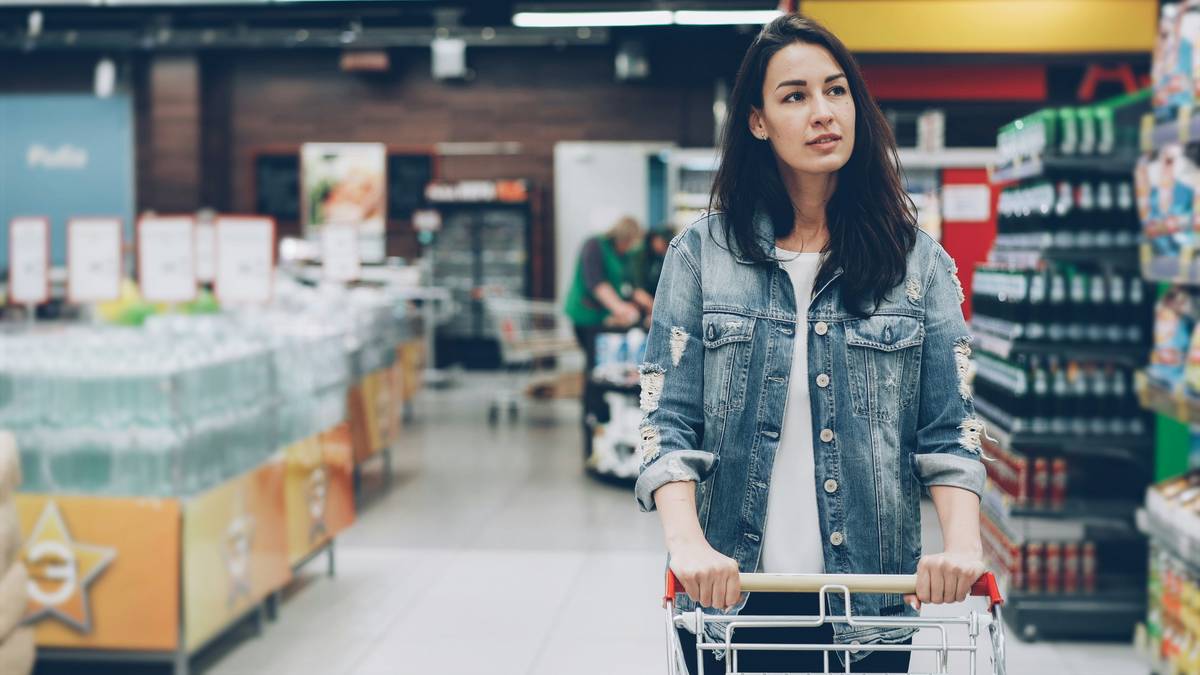 A basket filled with fresh produce and snacks in a grocery store aisle