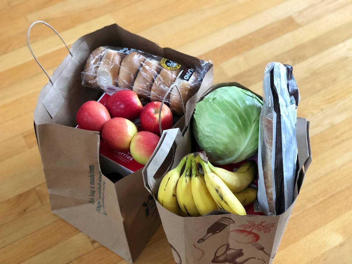 Photo of a happy customer holding a reusable grocery bag full of discounted items