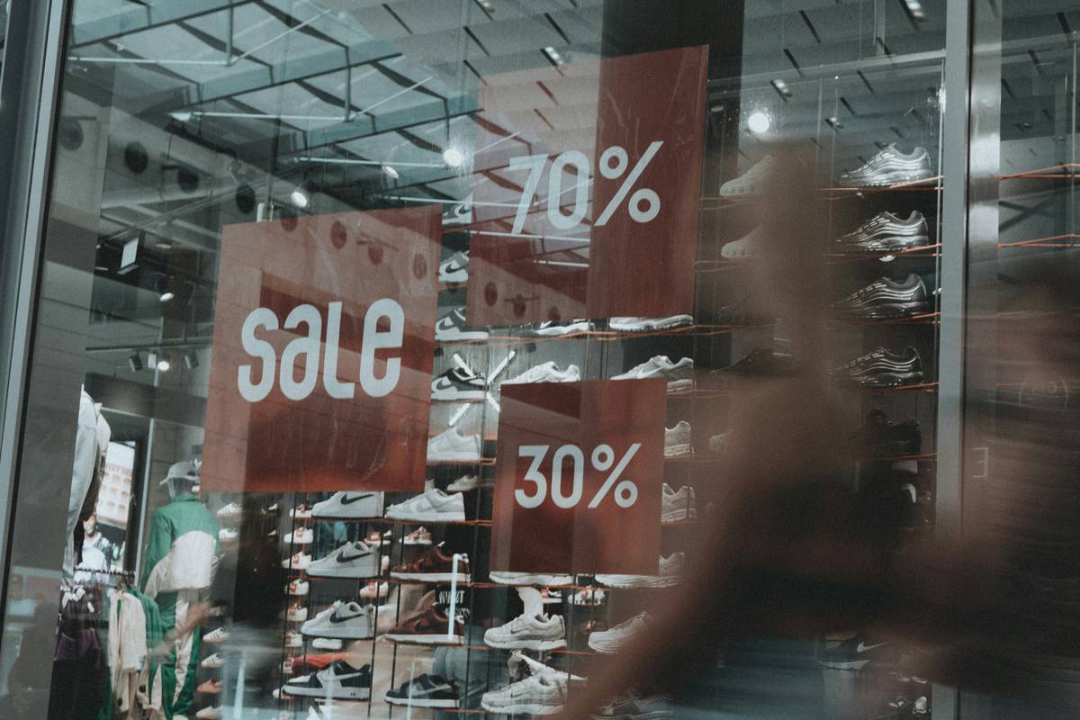 Smiling couple pushes a loaded shopping cart full of discounted groceries.