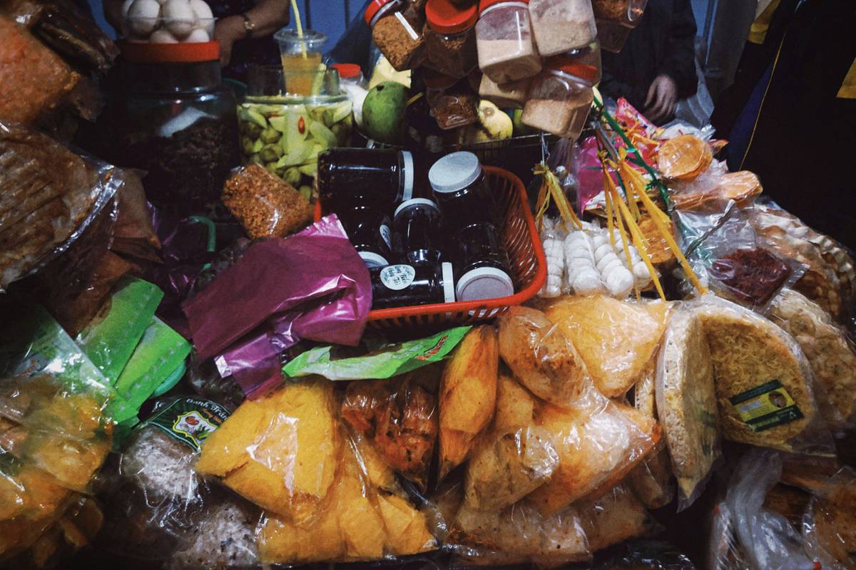 A person holding a shopping basket filled with fresh produce and checking their list.
