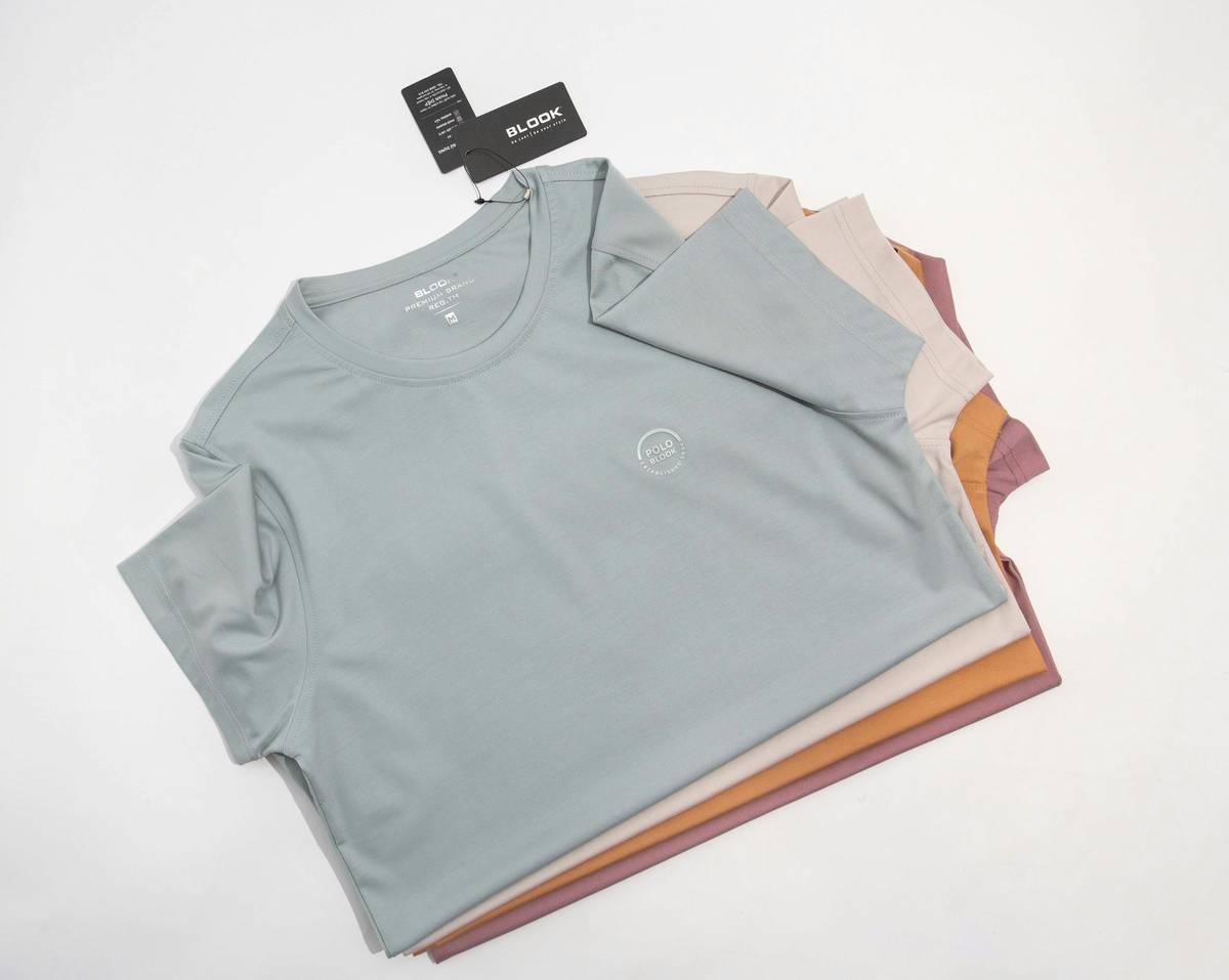 A woman browsing racks of colorful tops at a local market.