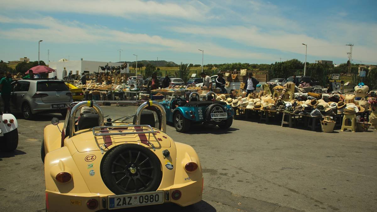 Outdoor market with vintage cars and stalls