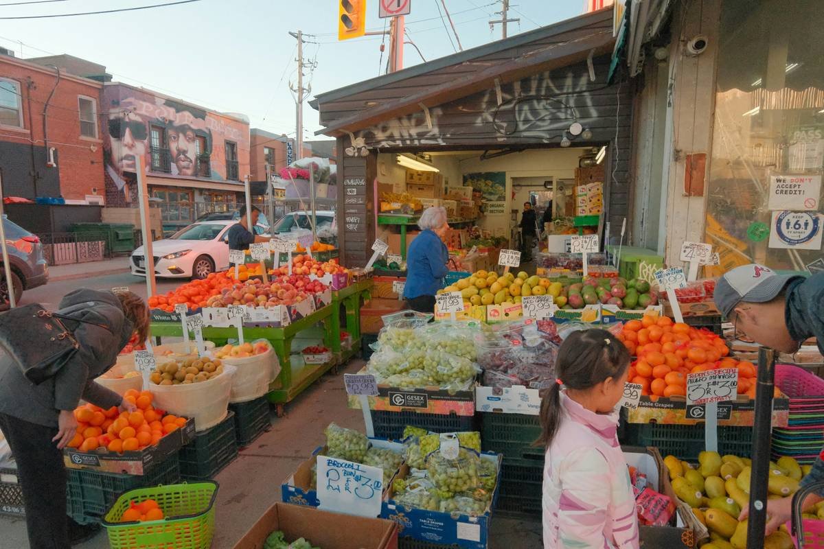 People shop at an outdoor fruit and vegetable market.