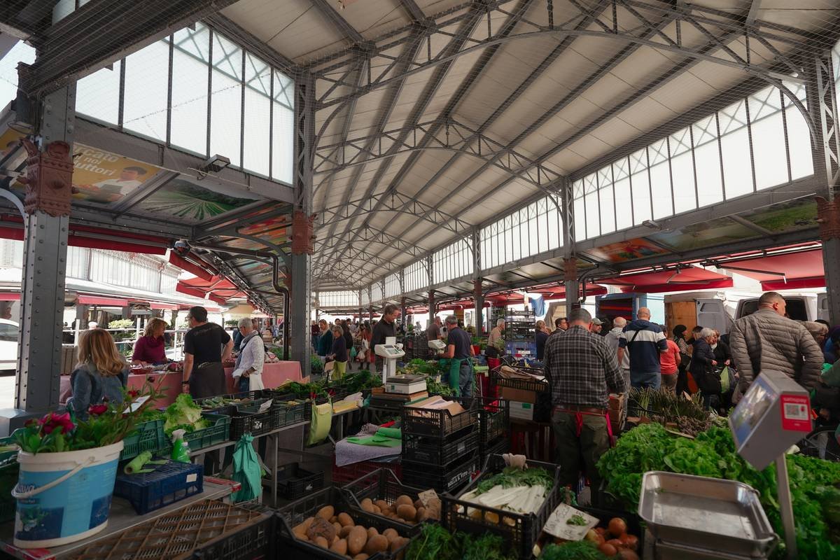 A bustling weekly market with fresh fruits, vegetables, and shoppers holding reusable bags — illustrating what are weekly markets